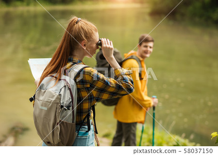 ginger hiker in checked shirt using her binocular 58037150