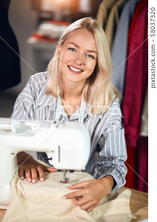charming positive woman repairing clothes in the room. 58037320