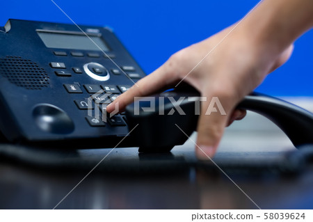 Hand touch number for calling to custommer,Closeup ip phone black color on the wood floor, Bussiness connection concept 58039624
