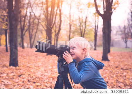 Little blond boy takes pictures on a SLR camera. Little blond boy takes pictures on a SLR camera. 58039821