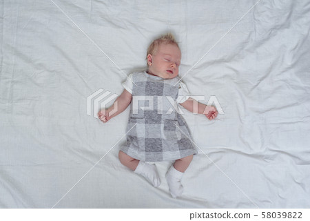 Sleeping newborn girl in a dress on a white sheet. Sleeping newborn girl in a dress on a white sheet. 58039822