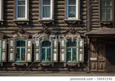 Window with the wooden carved architrave in the old wooden house in the old Russian town. Irkutsk Window with the wooden carved architrave in the old wooden house in the old Russian town. Irkutsk 58041540