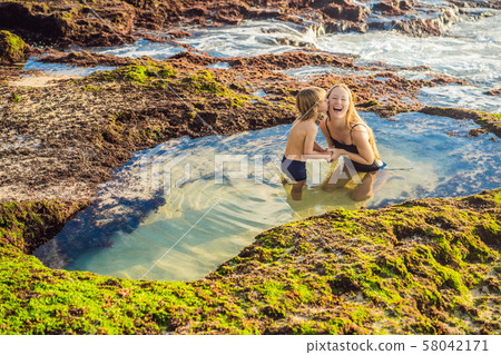 Mother and son tourists on Pantai Tegal Wangi Beach sitting in a bath of sea water, Bali Island 58042171