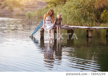 Mother and daughter sitting on the pier 58042249