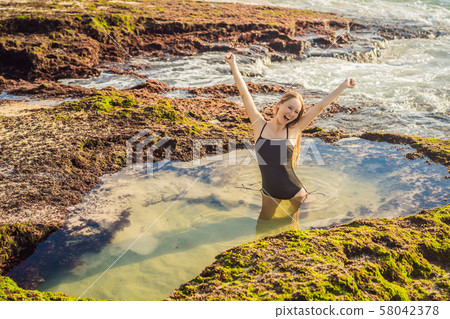 Young woman tourist on Pantai Tegal Wangi Beach sitting in a bath of sea water, Bali Island 58042378