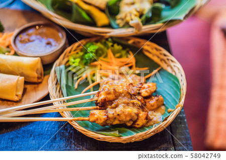 Satay or sate, skewered and grilled meat, served with peanut sauce, cucumber and ketupat Satay or sate, skewered and grilled meat, served with peanut sauce, cucumber and ketupat 58042749