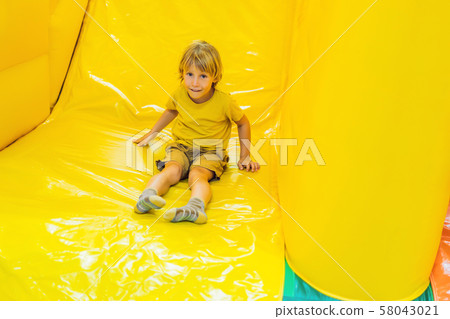 The boy rides with an inflatable slide The boy rides with an inflatable slide 58043021