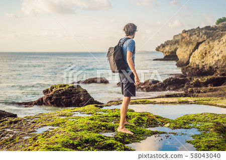 Young man tourist on Pantai Tegal Wangi Beach, Bali Island, Indonesia. Bali Travel Concept Young man tourist on Pantai Tegal Wangi Beach, Bali Island, Indonesia. Bali Travel Concept 58043040