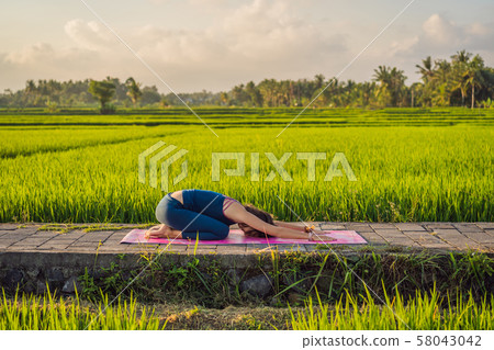 Young woman practice yoga outdoor in rice fields in the morning during wellness retreat in Bali Young woman practice yoga outdoor in rice fields in the morning during wellness retreat in Bali 58043042