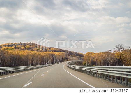 Amazing view with colorful autumn forest with asphalt mountain road. Beautiful landscape with empty 58043187