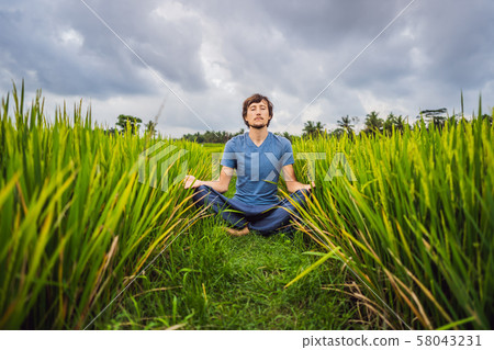 Man doing yoga in a rice field 58043231