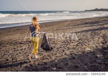 Young woman cleaning up the beach. Natural education of children 58043240