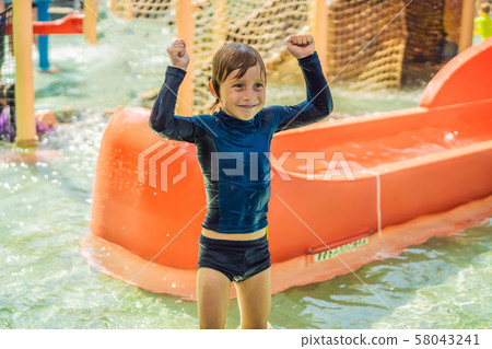 Happy boy on water slide in a swimming pool having fun during summer vacation in a beautiful Happy boy on water slide in a swimming pool having fun during summer vacation in a beautiful 58043241