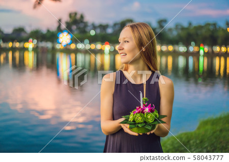 A female tourist holds the Loy Krathong in her hands and is about to launch it into the water. Loy 58043777