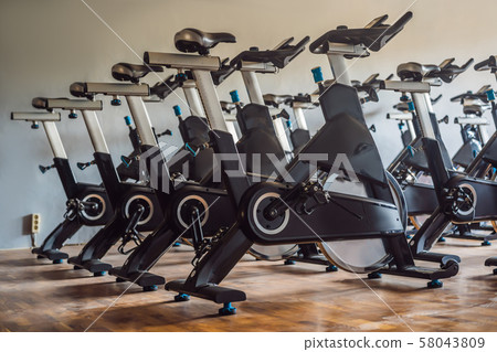 Aerobics spinning exercise bikes gym room with many in a row 58043809