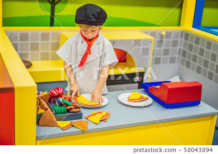 The boy plays in the toy kitchen, cooks a pizza 58043894