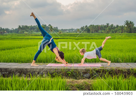 Boy and his yoga teacher doing yoga in a rice field 58043903