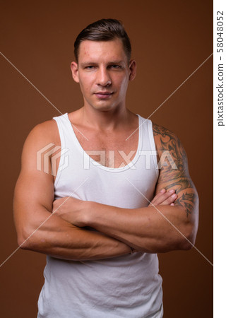 Studio shot of muscular man against brown background 58048052