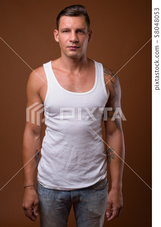 Studio shot of muscular man against brown background Studio shot of muscular man against brown background 58048053