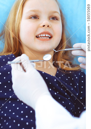 Little baby girl sitting at dental chair with open mouth during oral check up while doctor. Visiting Little baby girl sitting at dental chair with open mouth during oral check up while doctor. Visiting 58055069