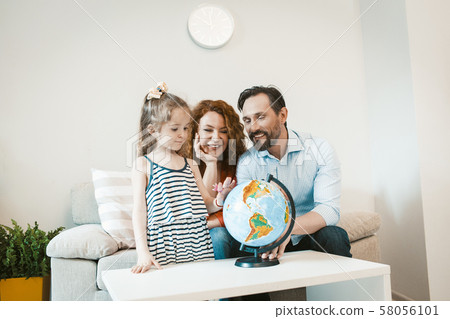 Going on adventure, mom, dad and daughter studying globe.