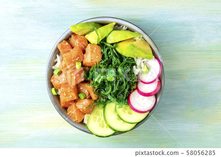Salmon poke with avocado, wakame and cucumber, shot from above on a teal blue background with a 58056285