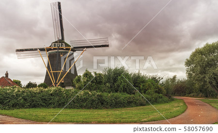 Old wind mill at the dramatic cloudy sky in Holland. The Netherlands Old wind mill at the dramatic cloudy sky in Holland. The Netherlands 58057690