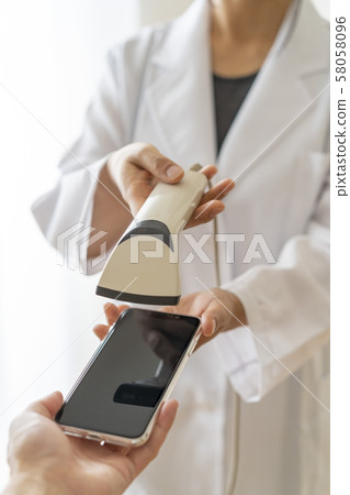 A pharmacist woman in a white robe scans barcodes for cashless payment customers at the time of payment A pharmacist woman in a white robe scans barcodes for cashless payment customers at the time of payment 58058096