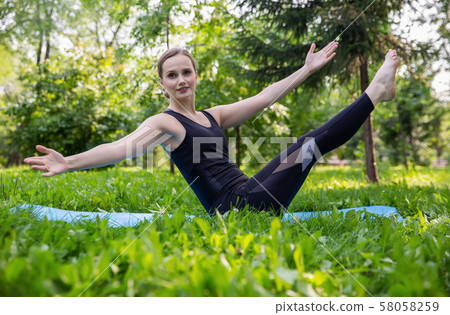 Beautiful woman doing Pilates in the green park 58058259