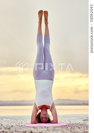 Woman doing headstand outdoors 58062043