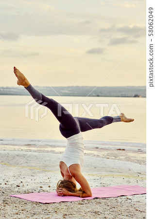 Yogi woman doing Salamba Sirsasana asana 58062049