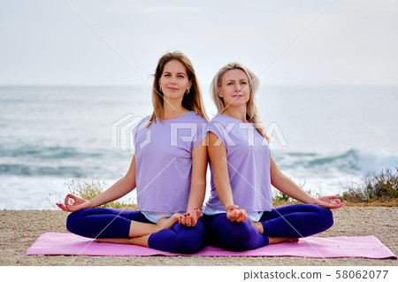 Women sit in lotus pose 58062077