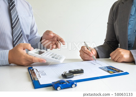 Car dealership provides advice about insurance details and car rental information and delivers the keys after signing the rental contract 58063133