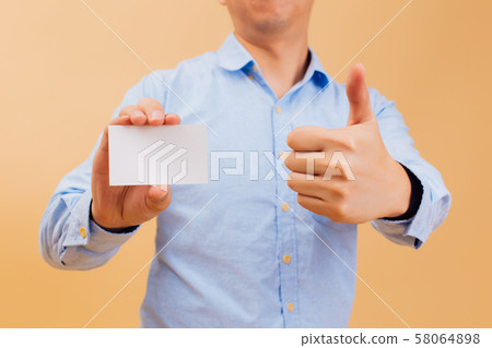Businessman hand showing empty white business card and giving thumbs up in yellow background Businessman hand showing empty white business card and giving thumbs up in yellow background 58064898
