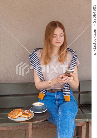 Charming woman with beautiful smile reading good news on mobile phone during rest in coffee shop Charming woman with beautiful smile reading good news on mobile phone during rest in coffee shop 58064909