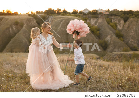 Stylish young boy gives a big flower to his mom in 58068795