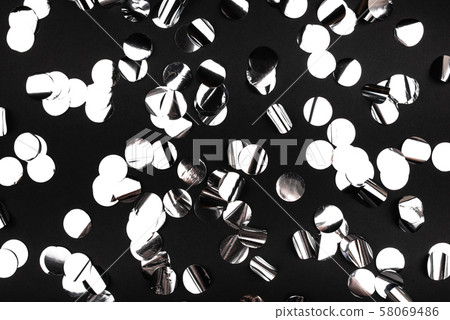 Silver confetti on black background. 58069486