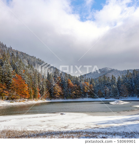 The first snow on a lake in a mountain forest The first snow on a lake in a mountain forest 58069901