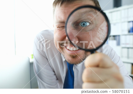 Smiling businessman hold magnifying glass 58070151