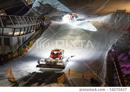 Two snowcat ratrack machines making night show performance on snow pister hill at alpine skiing 58070837
