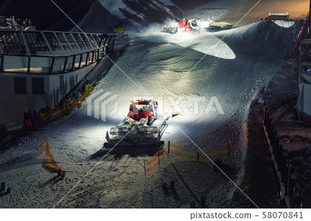 Two snowcat ratrack machines making night show performance on snow pister hill at alpine skiing 58070841