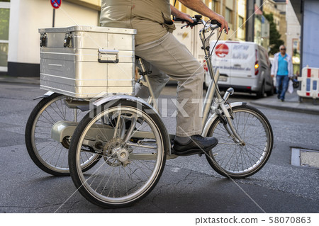 Unrecognizable man ride on tricycle for adults with rear trunks for transporting loads, service of 58070863
