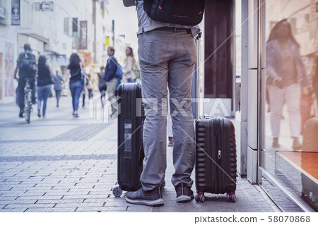Unrecognizable young man traveling with suitcases, city street, travel and tourism concept Unrecognizable young man traveling with suitcases, city street, travel and tourism concept 58070868