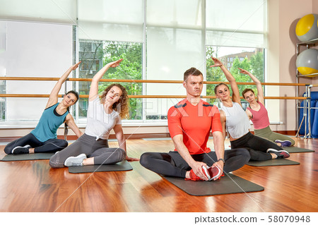 A group of sporting young people in sportswear, in a fitness room, doing push-ups or planks in the A group of sporting young people in sportswear, in a fitness room, doing push-ups or planks in the 58070948