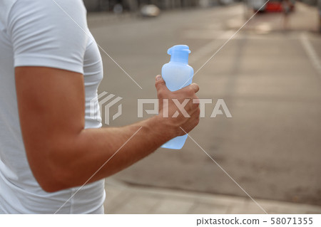 Man holding a bottle of water outdoors Man holding a bottle of water outdoors 58071355