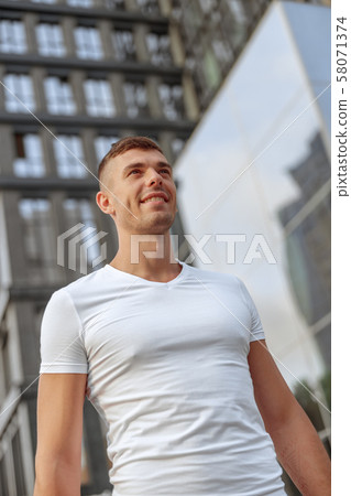 Smiling attractive Caucasian sportive man standing outside Smiling attractive Caucasian sportive man standing outside 58071374