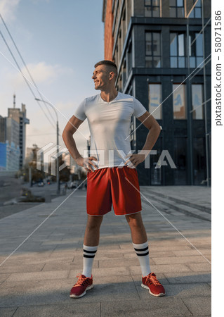 Cheerful attractive fit young man standing outside 58071586