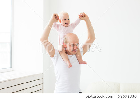 family, parenthood and fatherhood concept - happy father playing with little baby girl at home 58072336