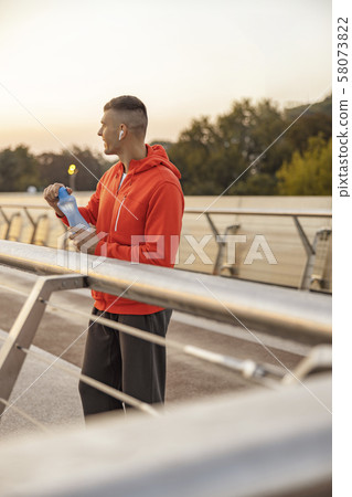 Contented sportive man with a bottle of water Contented sportive man with a bottle of water 58073822