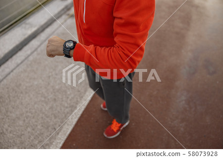 Caucasian runner looking at his wrist watch 58073928